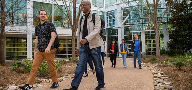 Two women sitting on a bench in front of a waterfall